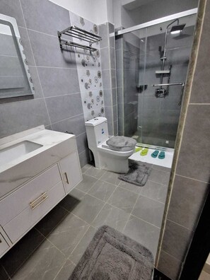 Een moderne badkamer met toilet, douche en wastafel.