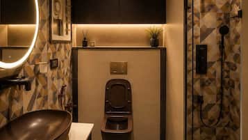 Un baño moderno con un espejo redondo, un lavabo a la vista, un inodoro y una zona de ducha.