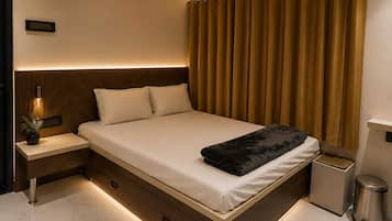 Quarto moderno com cama, mesas de cabeceira, lixeira e luminária fixada na parede.
