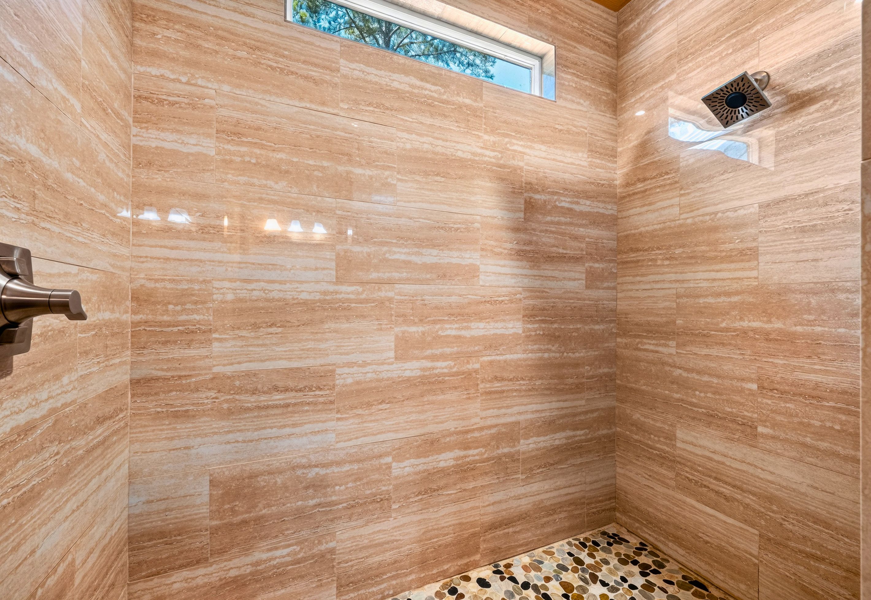 Une douche aux carreaux beiges et une petite fenêtre.