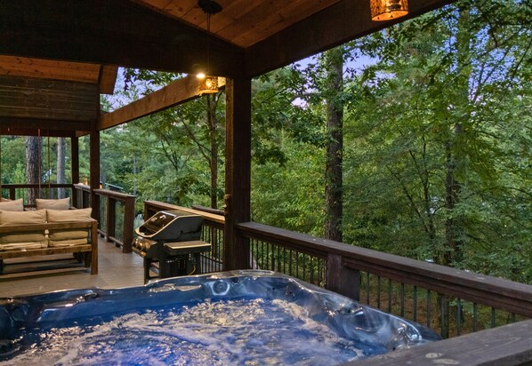 Ein Whirlpool auf einer Holzterrasse mit Blick auf einen Wald.