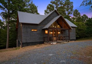 Eine rustikale Holzhütte mit Metalldach, Holzverkleidung und einer Veranda, auf der ein hölzernes Wasserrad steht.