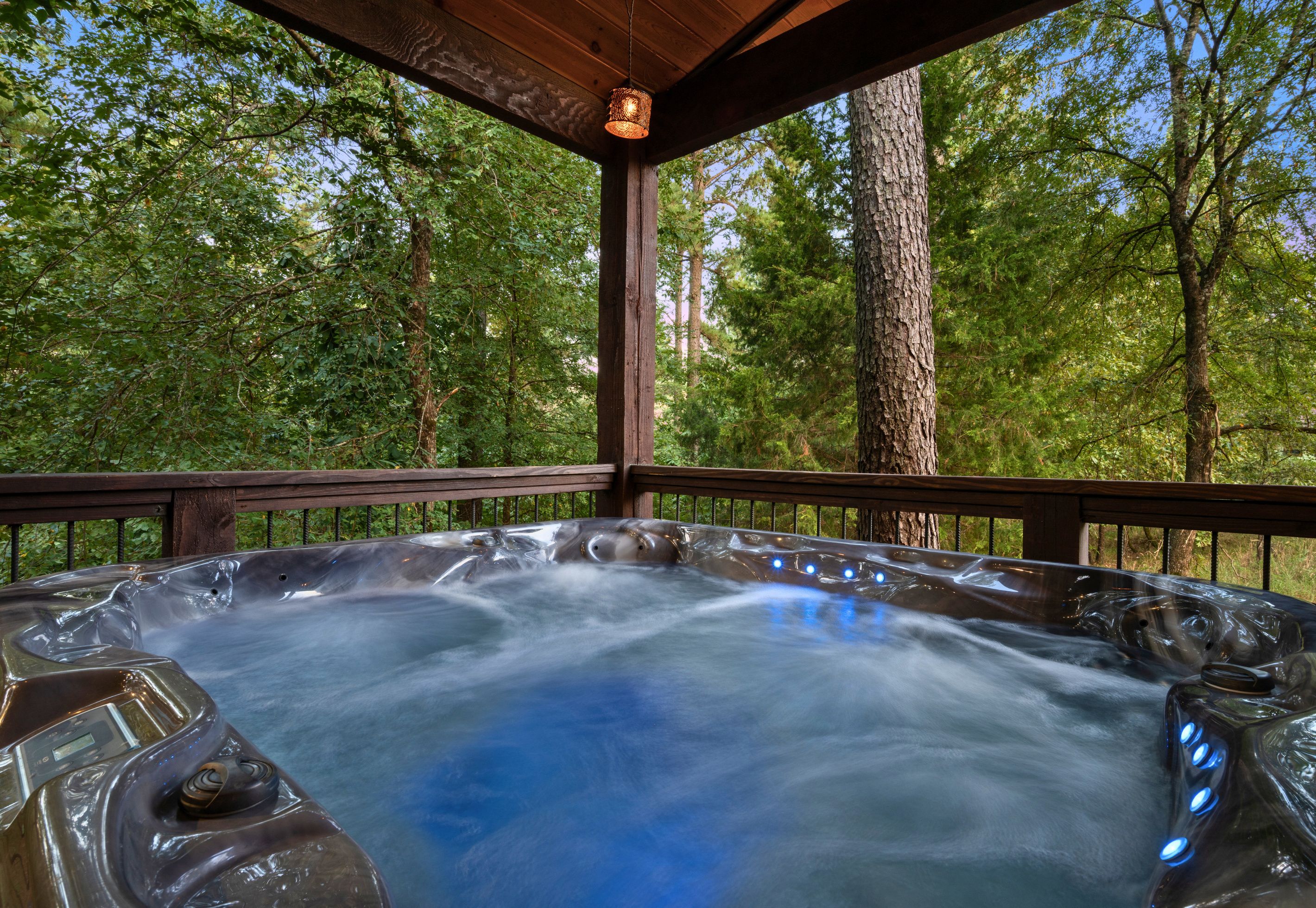 A hot tub in a wooden deck surrounded by trees.