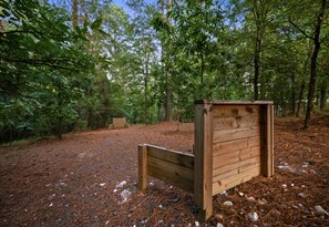 A wooden bench in a forested area with a clear sky. - Game Loft | Hot Tub | Fire Pit | Boat Parking (Broken Bow)