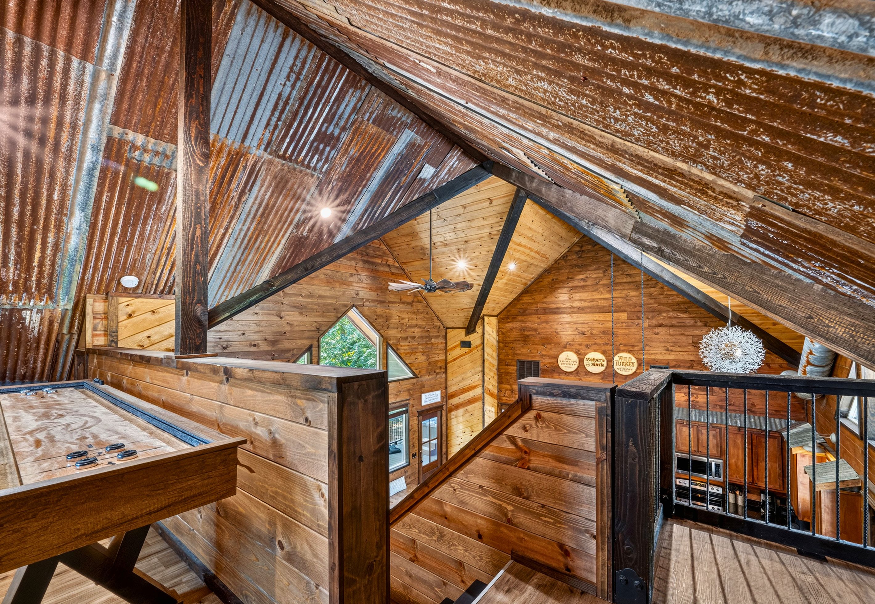 Un intérieur rustique avec des éléments en bois, un plafond en pente, une table en bois et un escalier menant à un niveau supérieur.