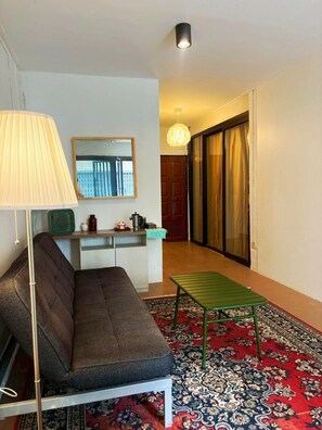 A living room with a sofa, a small table, a lamp, a mirror, and a patterned rug. - Charoennakhon 14 (Krung Thep Maha Nakhon)