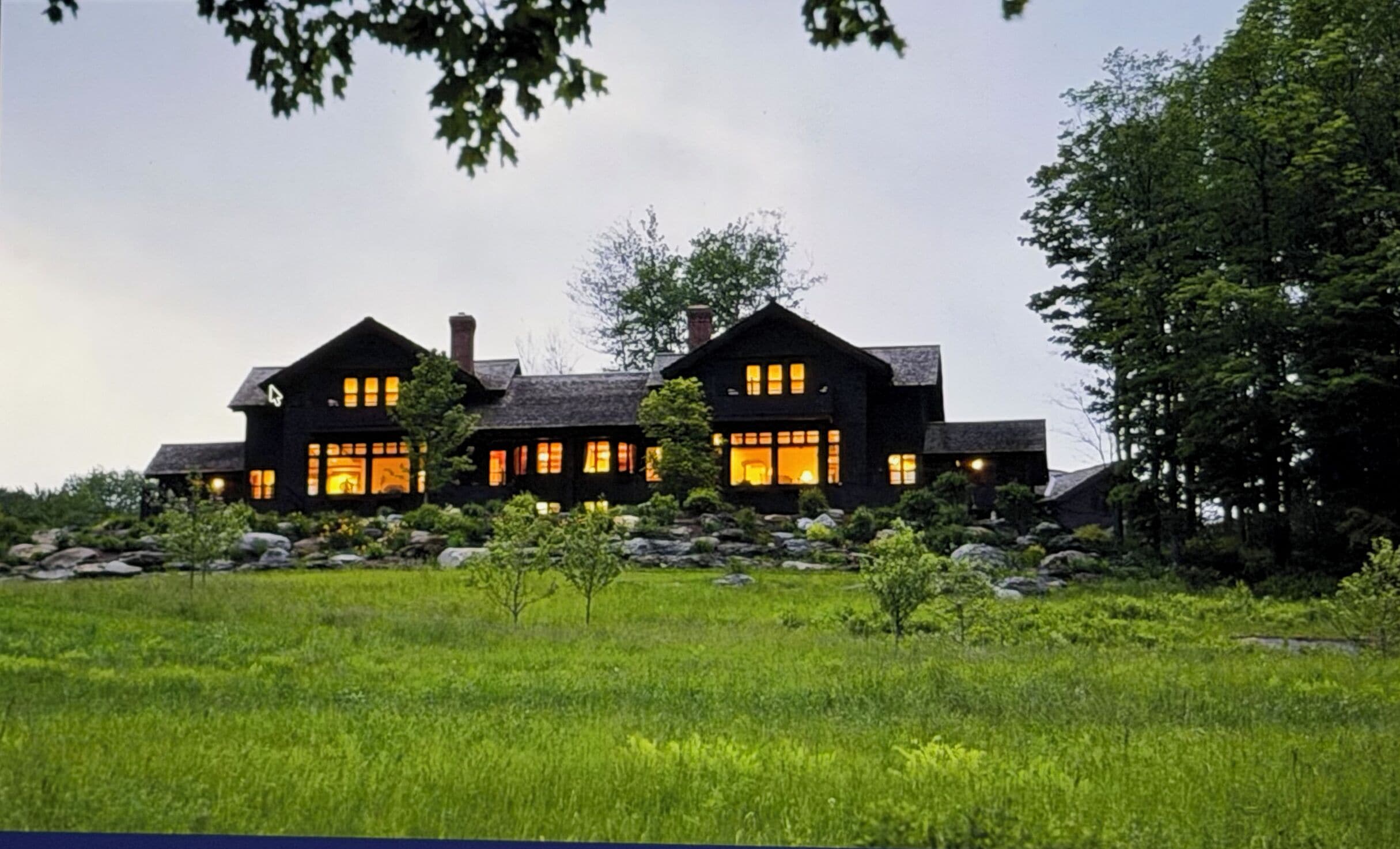 A two-story house with a symmetrical design, featuring large windows and a stone facade.