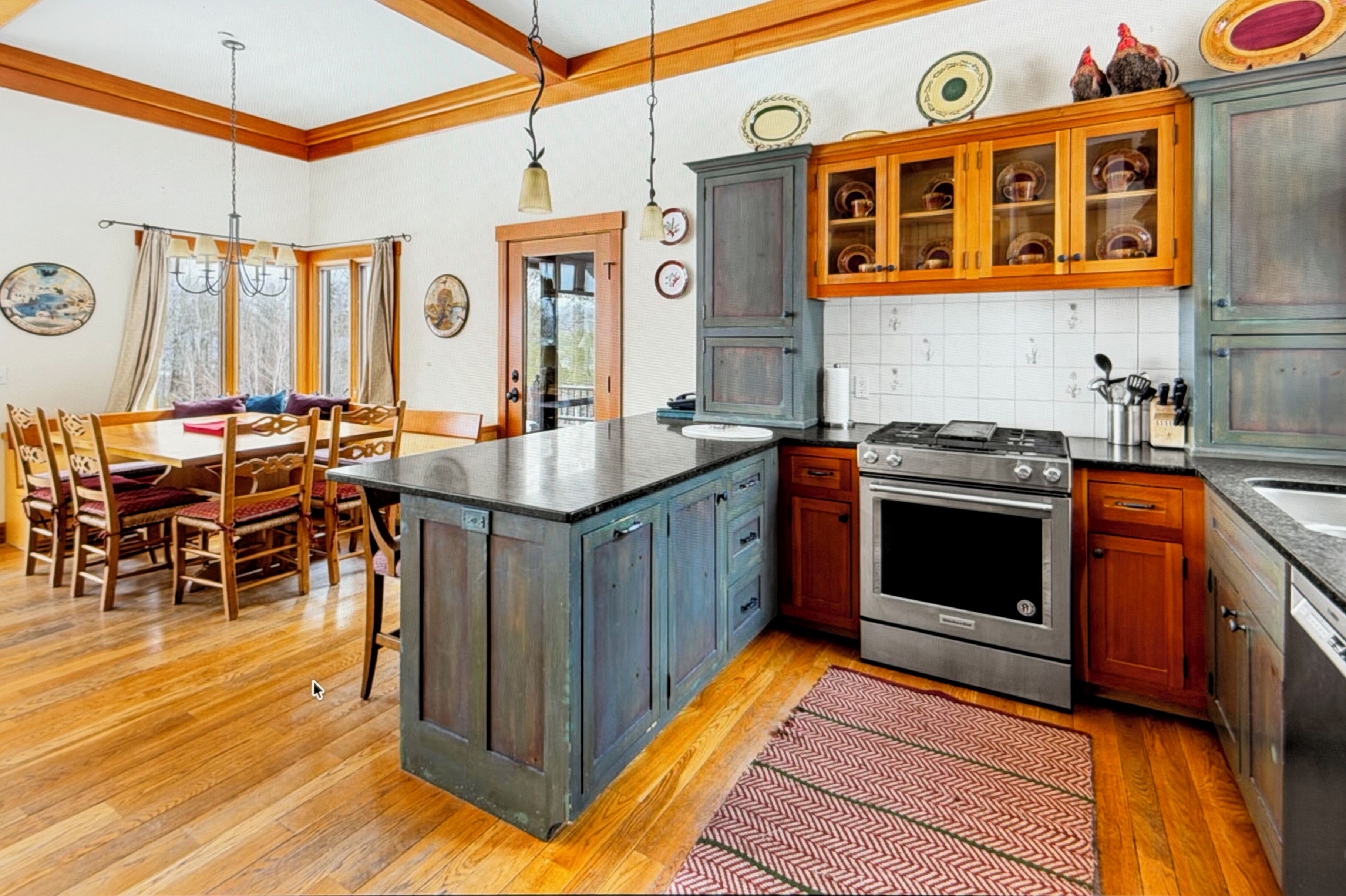 A kitchen with wooden cabinets, a central island, and a dining area with a table and chairs.