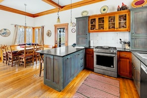A kitchen with wooden cabinets, a central island, and a dining area with a table and chairs.