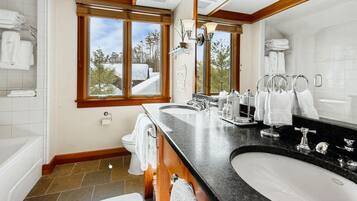A bathroom with a large window, a double sink, and a bathtub.