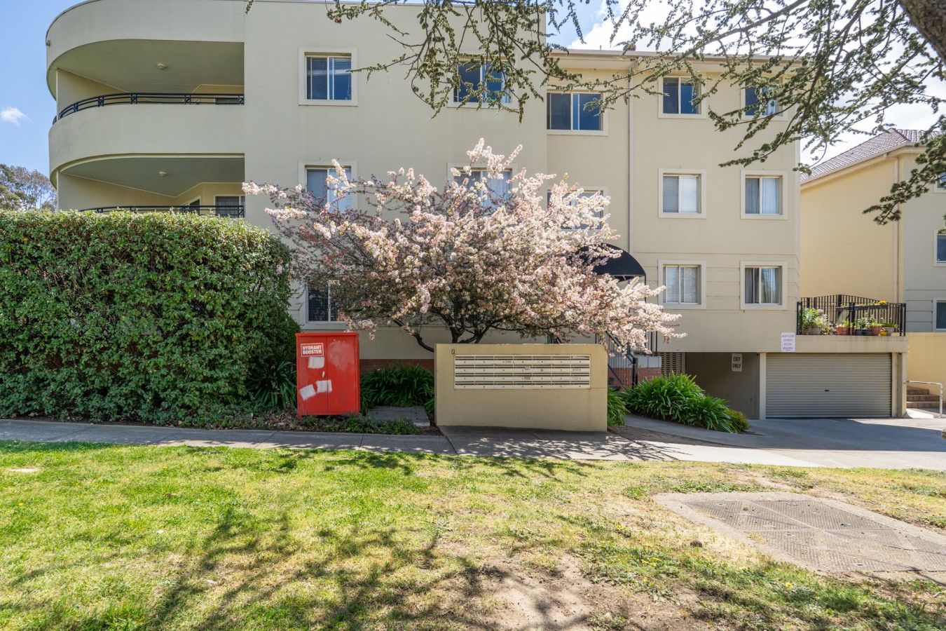 A multi-story residential building with a flat roof, a red mailbox, and a signboard.