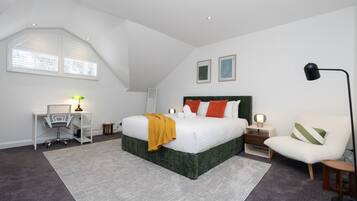 A bedroom with a bed, desk, chair, and a lamp.