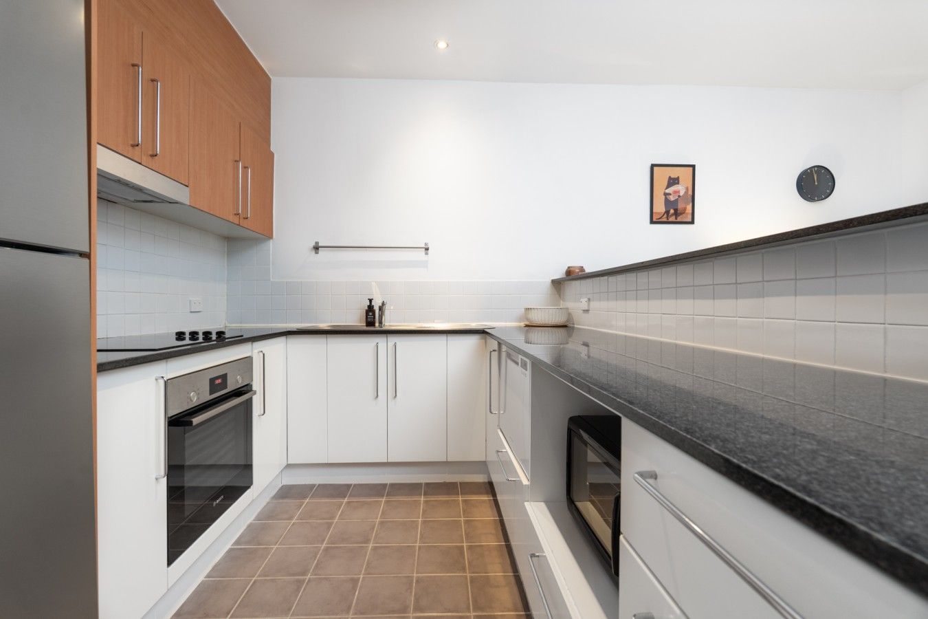 Een moderne keuken met witte kasten, een zwart aanrecht en een betegelde achterwand.