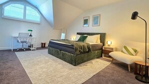 A bedroom with a bed, a desk, a chair, a floor lamp, and a window with blinds. - Eclectic 1BR With Private Terrace Near Manuka (Forrest)