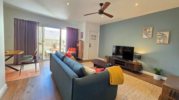 A modern living room with a sofa, television, and a ceiling fan. - Eclectic 1BR With Private Terrace Near Manuka (Forrest)