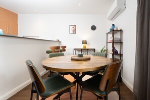 Ein Essbereich mit einem runden Holztisch, vier Stühlen, einer Lampe und einem Bücherregal.