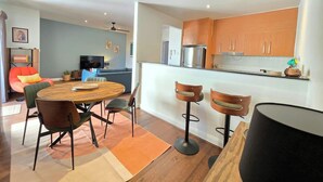 A modern kitchen with wooden cabinets, a dining area with a round table and chairs, and a bar stool. - Eclectic 1BR With Private Terrace Near Manuka (Forrest)