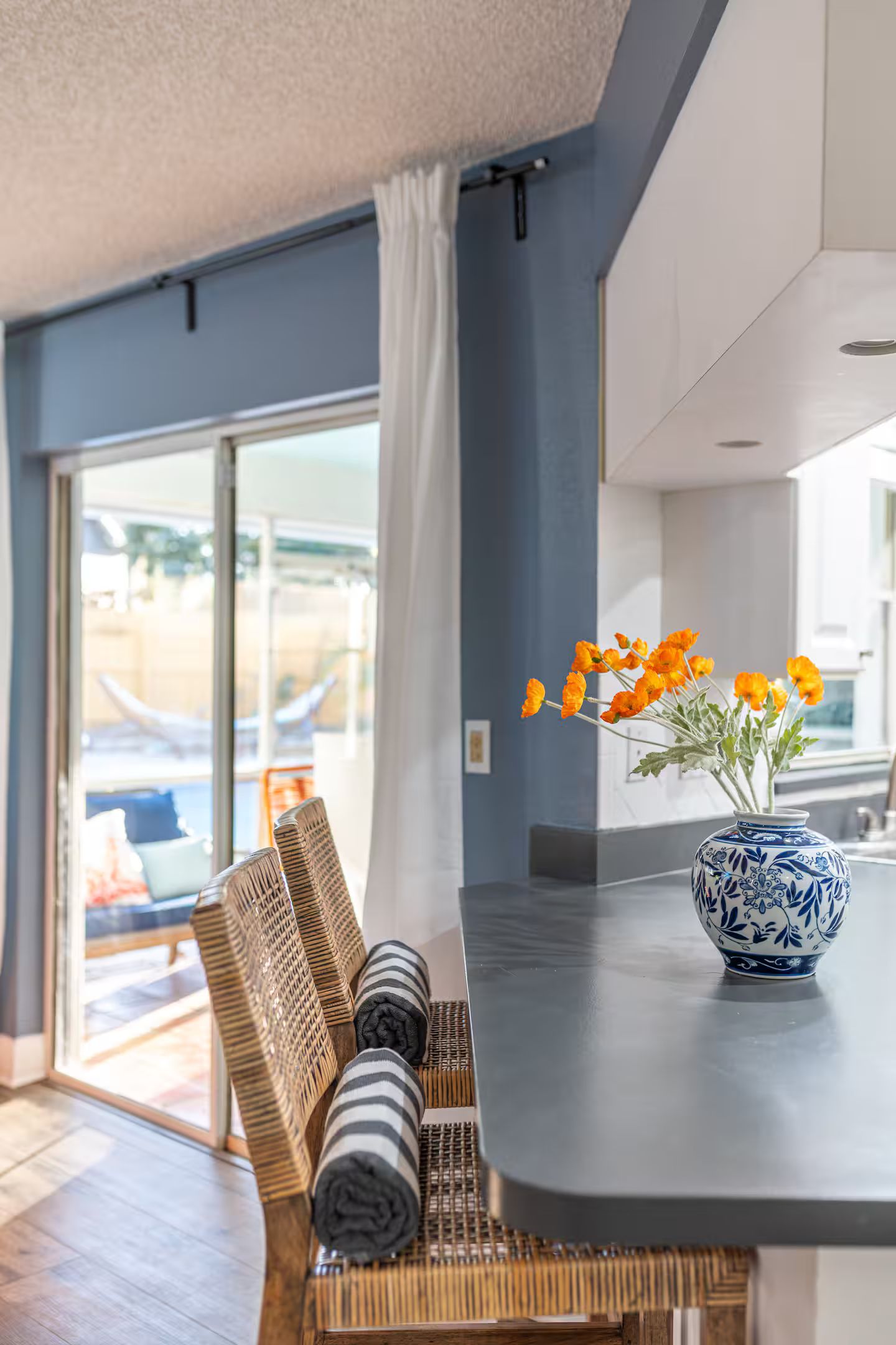 Un interior moderno con una zona de estar, un jarrón con flores y una vista a través de un ventanal.
