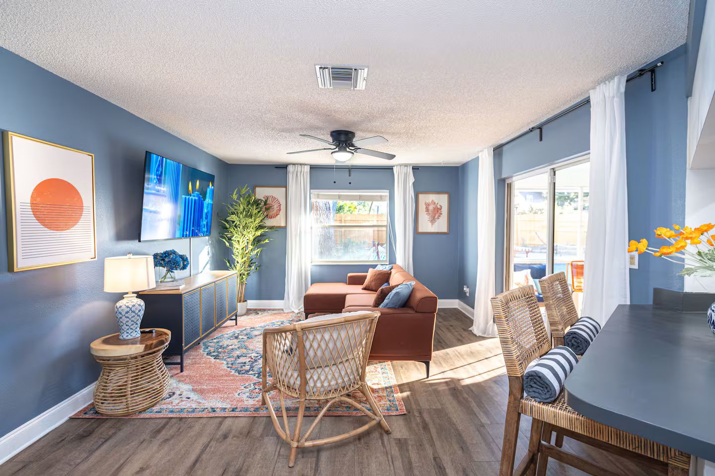 A modern living room with a sofa, a dining table, and a ceiling fan.