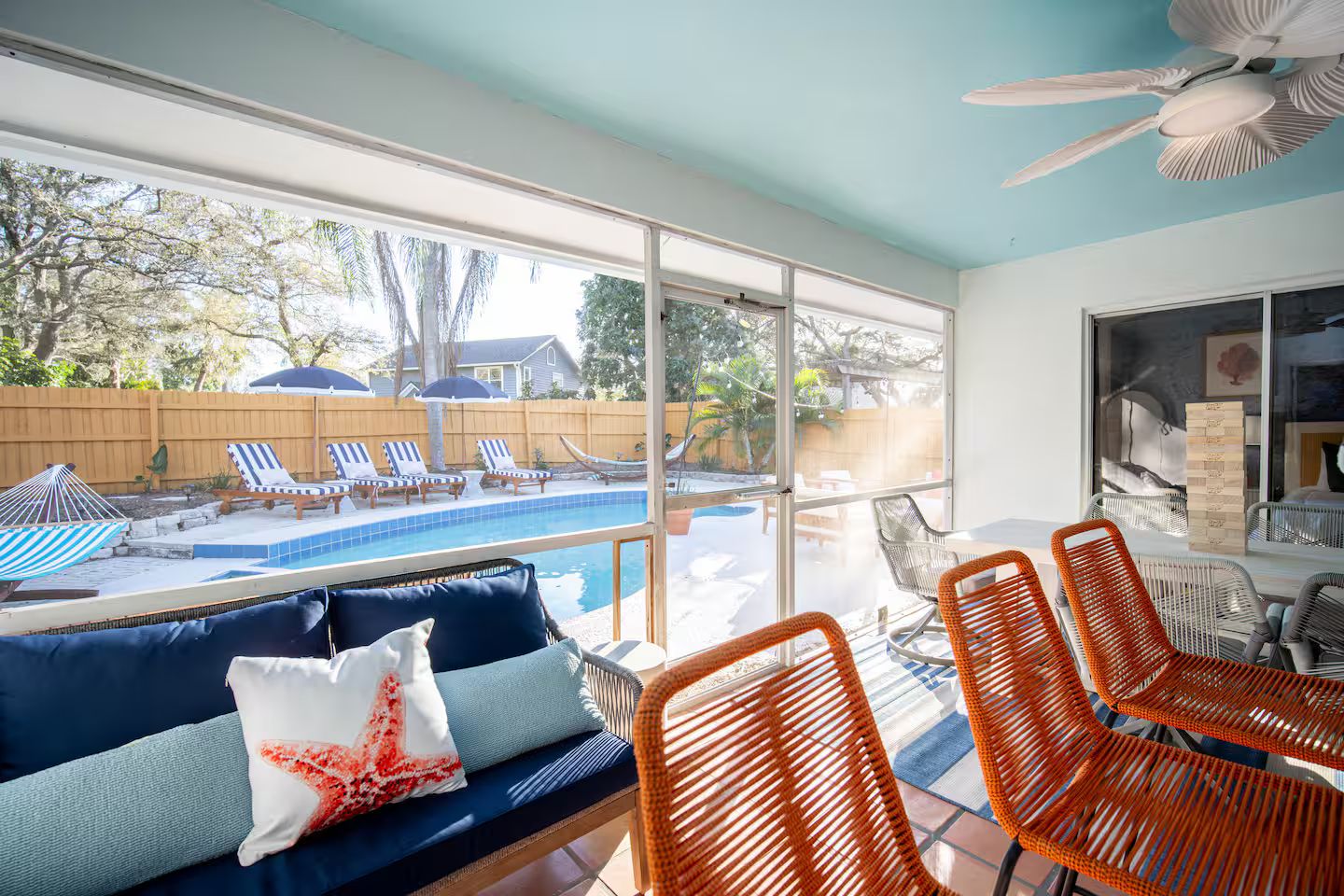 A room with a view of a swimming pool, a ceiling fan, and a seating area with a sofa and chairs.