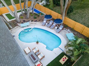 A backyard with a swimming pool, lounge chairs, and a small play area. - Palm Harbor Heated Pool Resort - Theater Mini Golf (Palm Harbor)