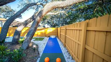 A backyard with a blue mat, two orange balls, a wooden fence, and trees.