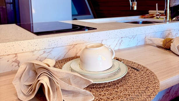 A kitchen area with a countertop, a coffee cup, a laptop, and a refrigerator.