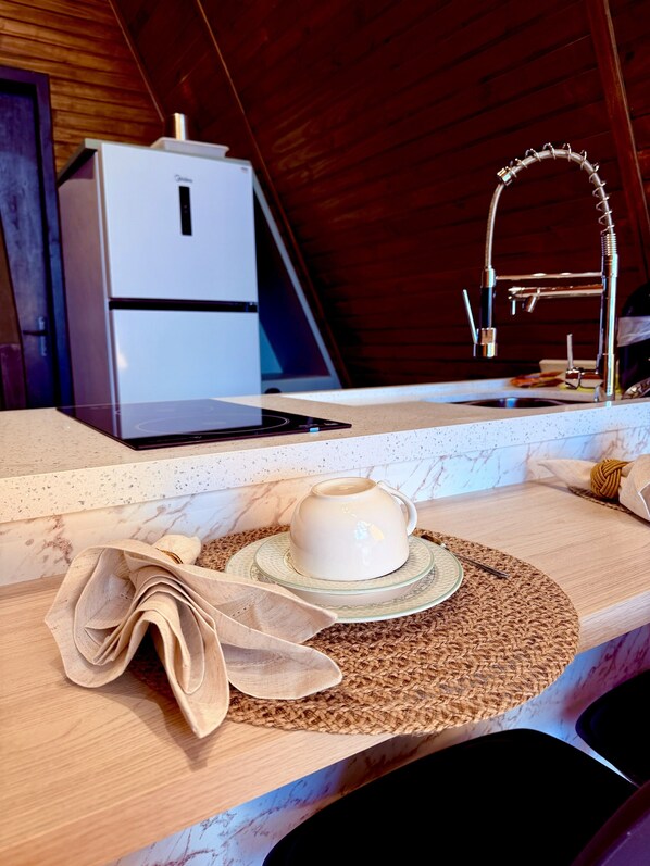Una cocina con mostrador, una taza de café, una computadora portátil y un refrigerador.