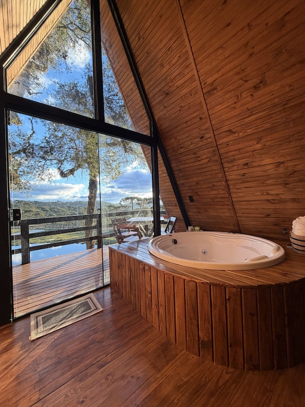 Un intérieur en bois avec un jacuzzi, de grandes fenêtres et une vue sur l’extérieur.
