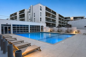 A modern hotel with a swimming pool, sun loungers, and a multi-story building with balconies. - Royan : appartement de prestige en bord de mer (Royan)