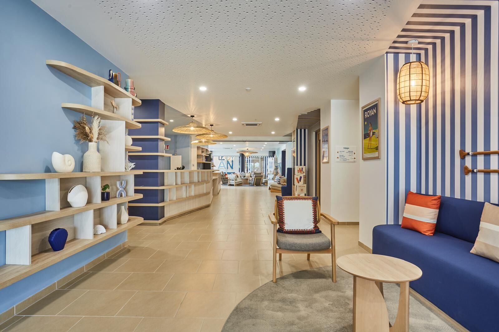 A hotel lobby with a reception desk, seating area, and a view into the dining area.