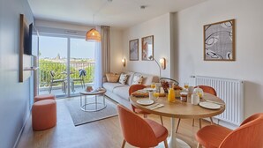 Uma sala de estar moderna com área de jantar, sofá, mesa de centro e varanda com mobiliário de exterior.