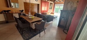 A dining area with a wooden table and four chairs, a sofa, and a television in a room with tiled flooring and a wooden ceiling. - CHRISTALLINES VILLA RESIDENCE (M'bour)