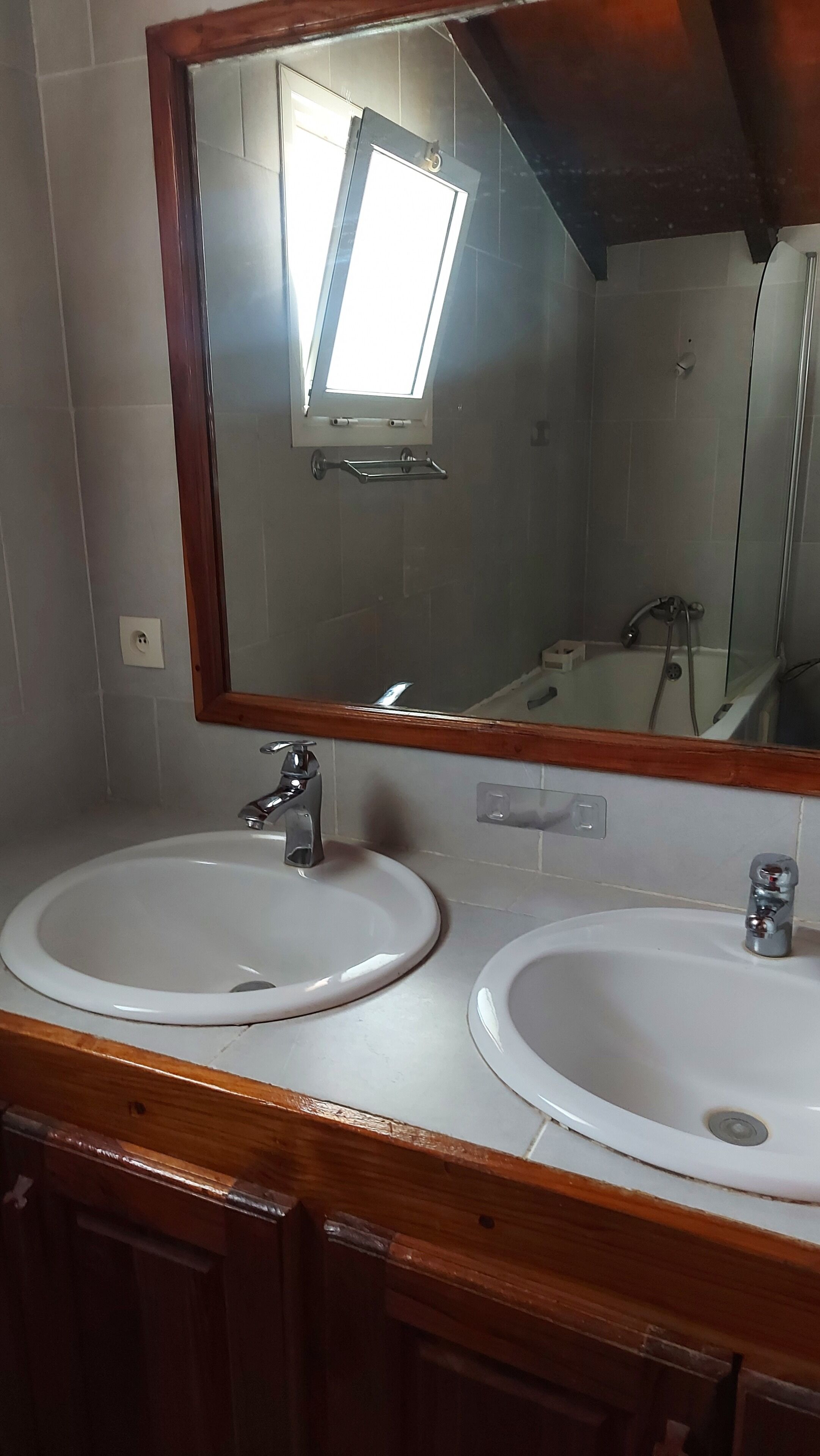 Un baño con dos lavamanos, un espejo y un tragaluz.