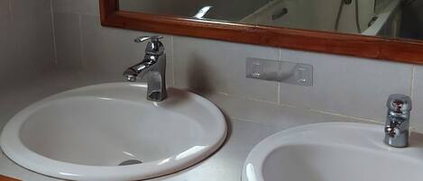 Un baño con dos lavamanos, un espejo y un tragaluz.