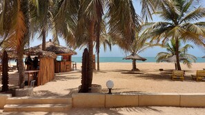 A beachside bar area with a thatched roof, wooden seating, and a view of the sea. - CHRISTALLINES VILLA RESIDENCE (M'bour)