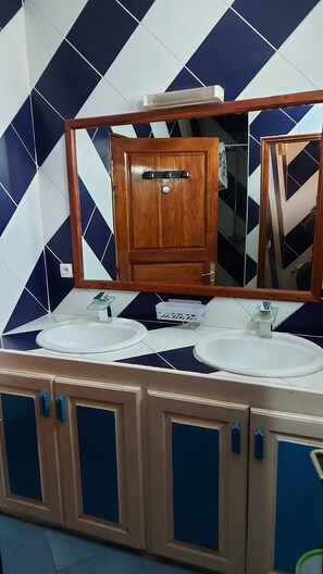A bathroom with two sinks, a wooden cabinet, and a mirror. - Vrbo Property (M'bour)