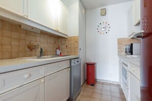 A kitchen with white cabinets, a dishwasher, a microwave, and a red trash bin. - Apartment, Air-Conditioned, Ocean View, Large Pool, Locked Garage (Nice)