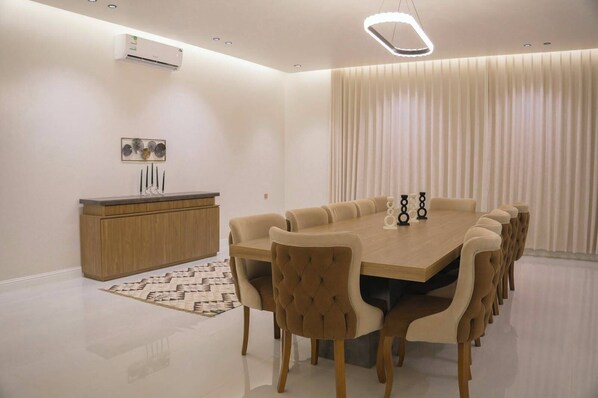 Un comedor moderno con una mesa larga y sillas a juego, un aparador de madera y una alfombra estampada.