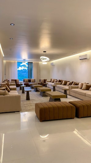 A modern living room with sofas, ottomans, and coffee tables arranged for socializing.
