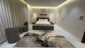 Une chambre à coucher moderne avec un lit, des tables de chevet, une chaise et un grand tapis à motifs abstraits.