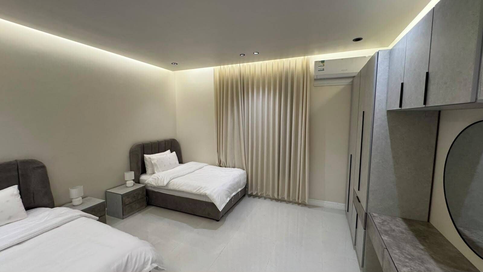 Una habitación de hotel moderna con cama, mesitas de noche, televisor y armario.