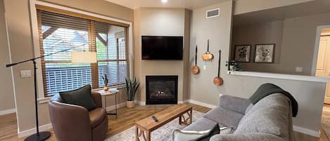 Una sala de estar con chimenea, televisor y sofá.