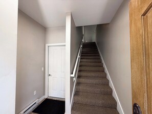 A staircase with carpeted steps leading to a door. - Long Term | 1 BR/1.5BA | Communal Pool & Hot Tub (Whitefish)