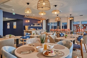 Ein Restaurant mit runden Tischen, Stühlen und hängenden Korbtischen.