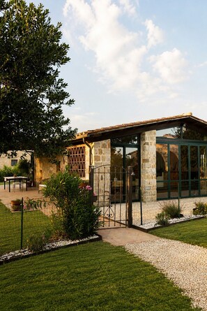 A stone building with a glass enclosure, surrounded by a well-maintained lawn and garden.