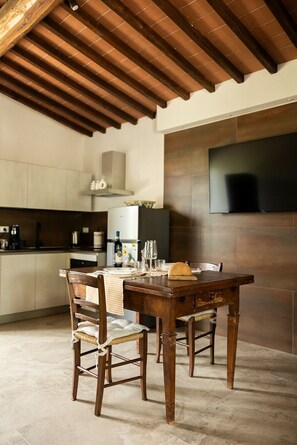 A rustic kitchen with a wooden table, chairs, and a tiled floor.