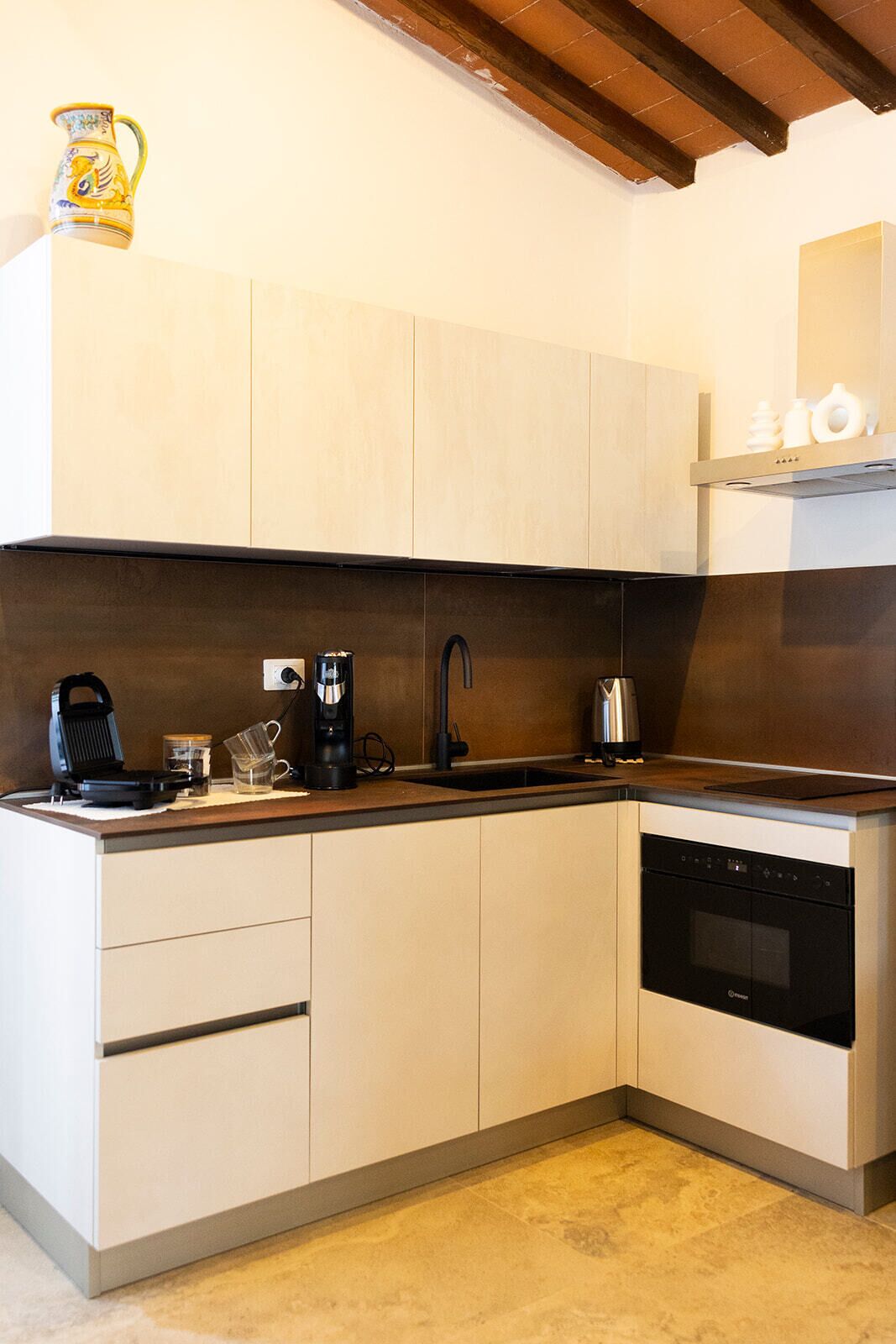 A kitchen with a built-in dishwasher, a coffee maker, and a kettle on the counter.