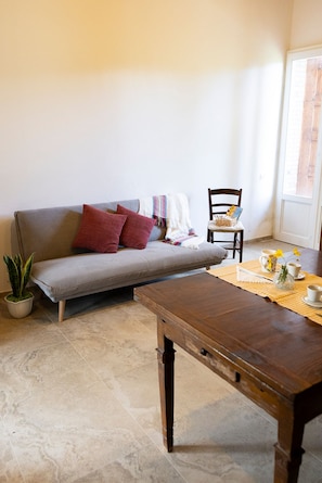 Ein Wohnzimmer mit einer Couch, einem Holztisch, einem Sessel und einer Topfpflanze.