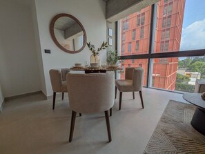 A modern living room with a dining area, large windows, and a view of a red building.